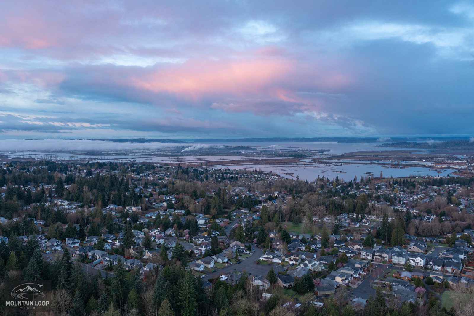 Aerial view over Marysville neighborhoods toward the Snohomish River delta and Everett at dusk